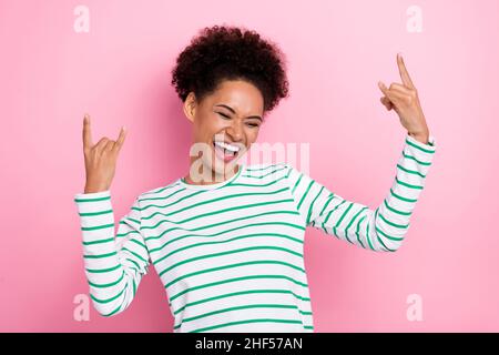 Portrait d'une jolie fille gaie montrant double corne ayant l'amusement danse isolé sur fond rose pastel couleur Banque D'Images