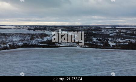 Vol sur un terrain enneigé.Des traces de labour agricole sont visibles sous la neige.Photographie aérienne. Banque D'Images