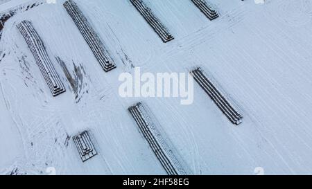 Vol sur un terrain enneigé.Les balles de paille sont empilées.Des traces de labour agricole sont visibles sous la neige.Photographie aérienne. Banque D'Images