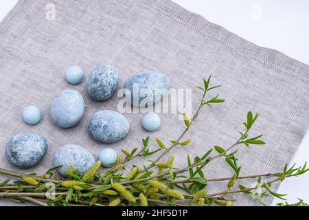 Œufs de Pâques en marbre et brindilles de saule sur une serviette en lin gris.Carte de vœux de Pâques.Photo horizontale. Banque D'Images