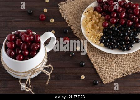 Baies variées de cerises, raisins de Corinthe blancs et noirs sont sur une table en bois.Photo horizontale. Banque D'Images