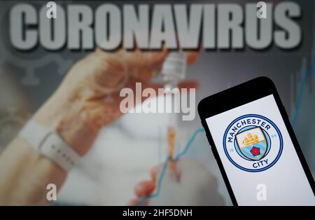 Photo du dossier datée du 09-01-2021 du logo du Manchester City football Club vu sur un téléphone portable avec une illustration du coronavirus sur un moniteur en arrière-plan.PEP Guardiola a révélé que Manchester City a subi de nouveaux cas de coronavirus au sein de son groupe de première équipe cette semaine.City n'avait pas 21 employés, dont le gérant Guardiola lui-même et sept joueurs seniors, pour la victoire du troisième tour de la coupe FA de la semaine dernière à Swindon après des tests positifs pour Covid-19.Date de publication : vendredi 14 janvier 2022. Banque D'Images