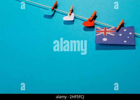 Drapeau australien avec des papiers en forme de coeur sur une corde à linge isolée sur fond bleu avec espace de copie Banque D'Images