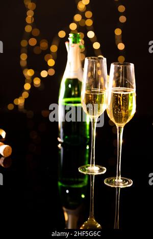 Gros plan de champagne dans les flûtes avec bouteille réfléchissant sur la table en verre Banque D'Images