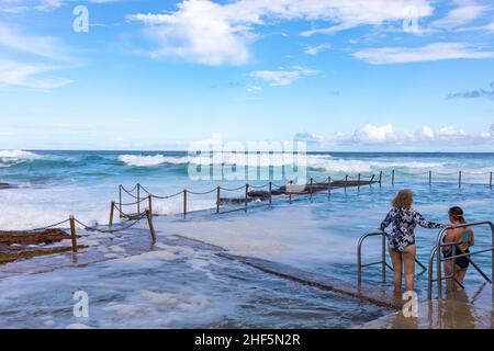 Deux dames se préparent à nager dans la piscine de roche de l'océan d'Avalon Beach alors que de grandes vagues s'écraseront dans la piscine et la plage, Sydney, Australie en fin d'après-midi Banque D'Images