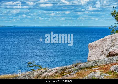 Lointain, petit voilier ou voilier voyageant seul en mer par l'île de Hano, Suède véhicule la paix ou la tranquillité lors de vacances d'été solitaires Banque D'Images
