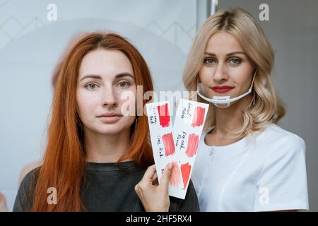 Un professeur permanent de maquillage présente un modèle de tutoriel.Très beau maître de lèvre et de sourcil dans son atelier.Portrait d'un maquilleur choisissant la couleur du maquillage permanent sur les lèvres Banque D'Images