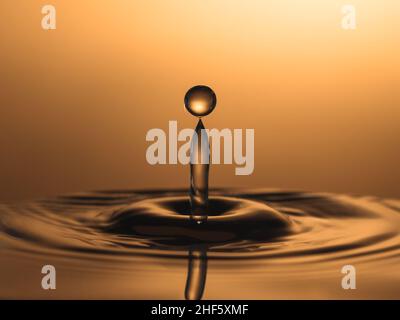 Photo macro d'une goutte d'or qui tombe dans elle Banque D'Images