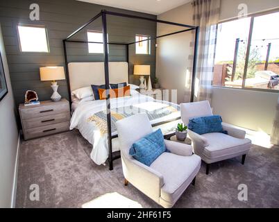 Chambre principale avec cadre de lit à baldaquin, tables de nuit, lampes et deux fauteuils Banque D'Images