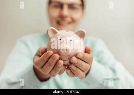 Femme d'affaires tenant une banque de pigeons avec des pièces de monnaie Banque D'Images