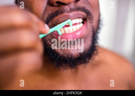 homme afro-américain nettoyant ses dents avec de la soie dentaire Banque D'Images