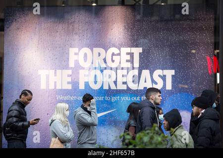 Les gens font la queue devant une publicité intitulée « Forget the Forecast » à l'extérieur d'un magasin Nike Town le lendemain de Noël dans le centre de Londres. Banque D'Images