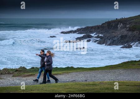 Un couple qui profite d'une marche rapide le long du sentier côtier de Towan Head pendant les conditions météorologiques orageux sur la côte nord de Cornwall. Banque D'Images