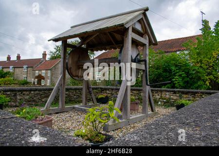 Cropton, Royaume-Uni - 5th octobre 2019 : ancien puits d'eau en bois d'époque, dans le pittoresque village rural de Cropton, Angleterre.Maison en pierre de retour Banque D'Images
