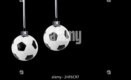 Ballons de football comme boules de Noël sur fond noir Banque D'Images