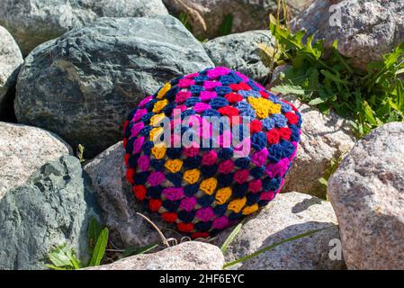 Un oreiller artisanal coloré en forme de crocheted, multicolore ; rouge, violet, bleu,et de la laine de coton de couleur jaune.Le motif textile de l'oreiller fait main est un flux Banque D'Images