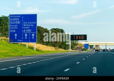 Leeds, Royaume-Uni - 23rd août 2019 : des voitures descendent l'autoroute britannique A1 avec des panneaux bleus indiquant les conducteurs vers Richmond, Leeds, Brough, Wetherby, Banque D'Images