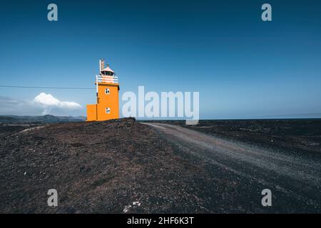 Phare avec volcan actif en arrière-plan, Hópsnesviti, Islande Banque D'Images