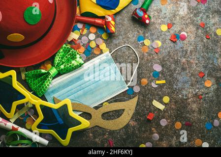 Concept de carnaval pendant le Covid-19.Vue de dessus des accessoires pour le carnaval avec masque chirurgical de protection sur fond de grunge.Célébration du Carnaval c Banque D'Images