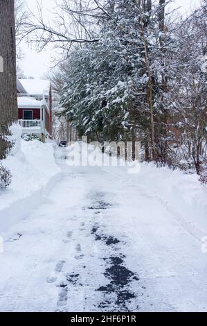 Maison de banlieue rouge et allée après la tempête de neige en février Banque D'Images