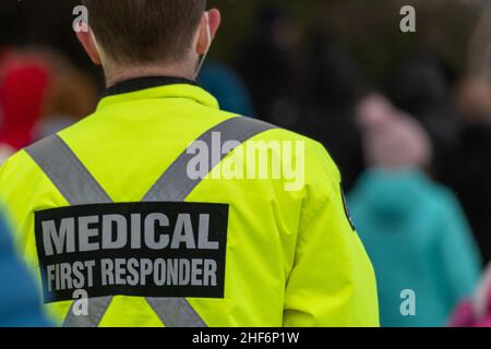 Premiers intervenants médicaux marchant le long d'une route portant des chapeaux de bas de Noël en laine noire, des manteaux réfléchissants jaunes avec le premier répondant médical en gris. Banque D'Images