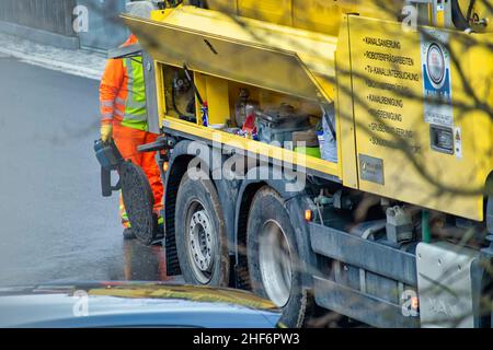 Entretien dans un trou d'homme avec un homme méconnaissable, travaillant derrière le véhicule de nettoyage des égouts dans la rue à Oberhaching, bavière, le 16th mars 2021. Banque D'Images