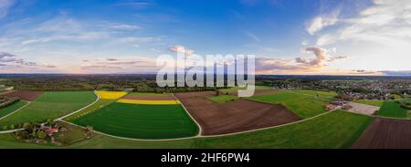 Magnifique paysage aérien d'une campagne rurale en vue panoramique le soir avec un lever de soleil entre quelques nuages Banque D'Images