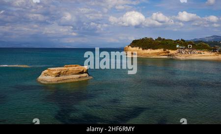 Grèce, Iles grecques, Iles Ioniennes, Corfou, côte nord,Formations rocheuses bizarres sur la côte, Canal d'amour, ciel bleu, nuages blancs, turquoise,mer bleue et verte, îlots rocheux au milieu de la distance, installations de plage en arrière-plan Banque D'Images