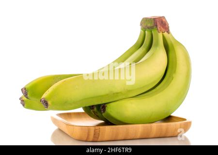 Un bouquet de bananes vertes biologiques sur une plaque de bambou, en gros plan, isolées sur du blanc. Banque D'Images