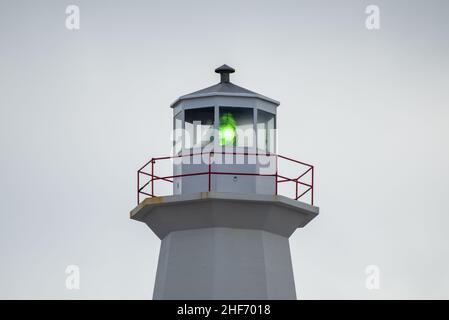 La salle d'observation d'un phare à huit côtés d'époque.La salle des lanternes dispose d'une grande ampoule verte.Le bâtiment en béton est blanc avec une rambarde blanche. Banque D'Images