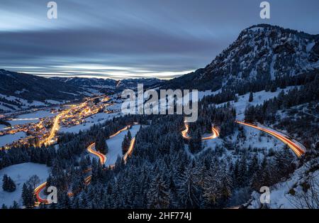 Bad Hindelang et Jochpassstrasse illuminés dans la soirée dans un paysage hivernal enneigé.Encadré par les Alpes enneigées de l'Allgäu.Bavière, Allemagne, Europe Banque D'Images
