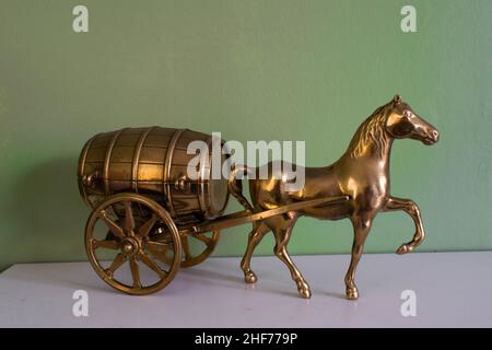 Ancien modèle de bronze cheval et baril de chariot sur une étagère avec un fond vert. Décoration, décoration, style de mode, arrière-plan. Banque D'Images