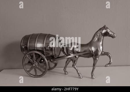 Ancien modèle de bronze cheval et baril de chariot sur une étagère avec un fond vert. Décoration, décoration, style de mode, arrière-plan. Banque D'Images