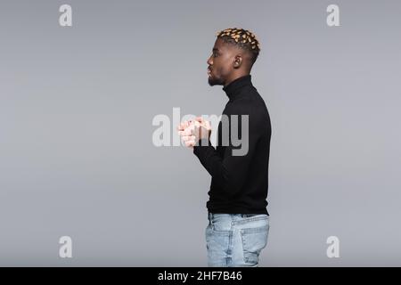 vue latérale de l'homme afro-américain avec peau de vitiligo et mains trempées isolées sur le gris Banque D'Images