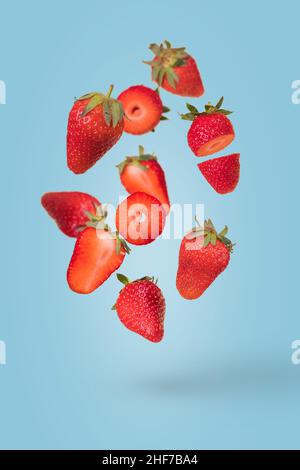 Composition créative avec des fraises mûres flottantes à léviter sur fond bleu.Vitamines, concept d'aliments frais et sains.Idée de fruit minimale.Tranché Banque D'Images