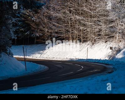 Route dans la forêt enneigée d'hiver.Montagnes des Vosges.Jour ensoleillé. Banque D'Images