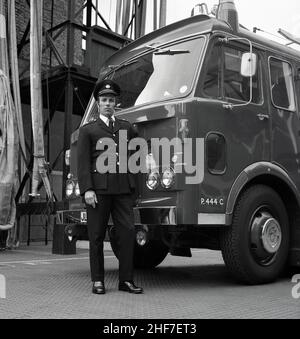 1960s, historique, un officier de station de la brigade des pompiers de Londres debout dans son uniforme par un moteur d'incendie Dennis à la caserne des pompiers de Lewisham, sud-est de Londres, Angleterre, Royaume-Uni.Les frères Dennis, John et Raymond, ont commencé à fabriquer et à vendre des bicyclettes en 1895, avant de progresser vers les voitures et les véhicules commerciaux et le légendaire moteur d'incendie. Banque D'Images