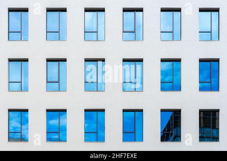 Vue abstraite de détail de la façade de bâtiment de bureau avec beaucoup de fenêtres bleues sur un mur blanc, et de réflexion.Papier peint de fenêtres abstraites Banque D'Images