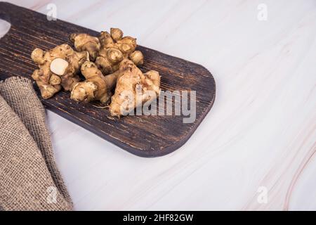 Les tubercules d'artichaut de Jérusalem se trouvent sur une planche en bois.Copier l'espace Banque D'Images