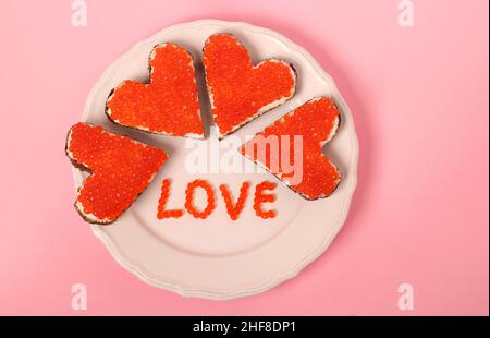 Canape avec caviar rouge et fromage à la crème en forme de coeur pour la Saint-Valentin sur fond rose. Vue de dessus Banque D'Images