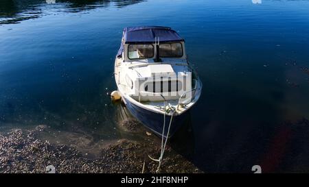 Petits bateaux amarrés dans un port de Cornouailles, eau bleu clair avec des reflets et des ombres Banque D'Images