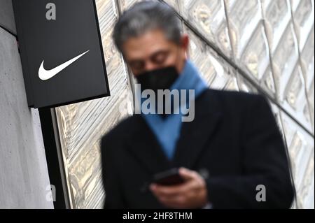 New York, États-Unis.14th janvier 2022.Un homme regarde son téléphone portable en passant devant le logo Nike « Swoosh » dans le magasin de chaussures de la Fifth Avenue à New York, NY, le 14 janvier 2022.Selon des rapports, Nike, une société américaine de fabrication de chaussures, prévoit de licencier des employés qui n'ont pas reçu d'exemption médicale ou religieuse dès janvier 15 ; les employés ont été informés en octobre 2021 de la mission de la société en matière de vaccination. (Photo d'Anthony Behar/Sipa USA) crédit : SIPA USA/Alay Live News Banque D'Images