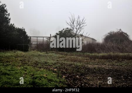 Porte qui mène à une grange lors d'une journée brumeuse en hiver Banque D'Images