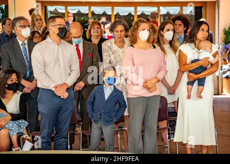 Masqués contre la pandémie du coronavirus, les candidats au baptême des adultes et leurs familles attendent patiemment leur tour dans une église catholique de Californie. Banque D'Images