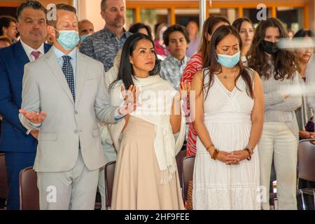 Masqués contre la pandémie du coronavirus, les candidats au baptême des adultes et leurs familles prient patiemment dans une église catholique de Californie. Banque D'Images