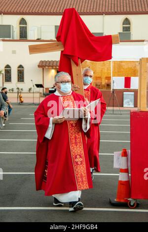 Dans le cadre d'une masse extérieure, les prêtres multiraciaux robed forment une procession alors qu'ils marchent une croix devant leur congrégation dans le stationnement d'une Souther Banque D'Images