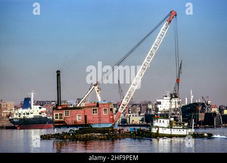 Un remorqueur pousse une grue flottante dans les eaux calmes du port de Boston.Notez les cargaisons. Banque D'Images