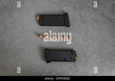 45 balles creuses et blouson plein métal de calibre ACP chargées dans des magasins de pistolet à main et des ronds non tirés alignés sur une surface en pierre Banque D'Images