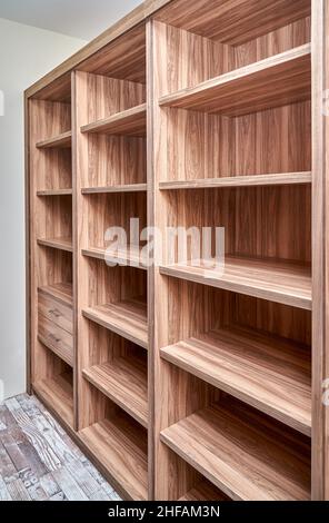 Armoire élégante en noyer massif et bois de placage avec étagères vides et tiroirs dans le dressing de l'appartement rénové Banque D'Images