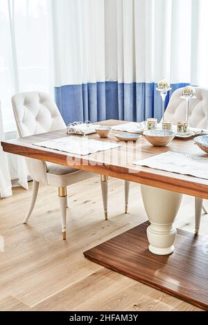 Table de salle à manger luxueuse et vintage en bois de noyer et de placage, cadre festif et fauteuils près de la fenêtre dans une chambre spacieuse Banque D'Images